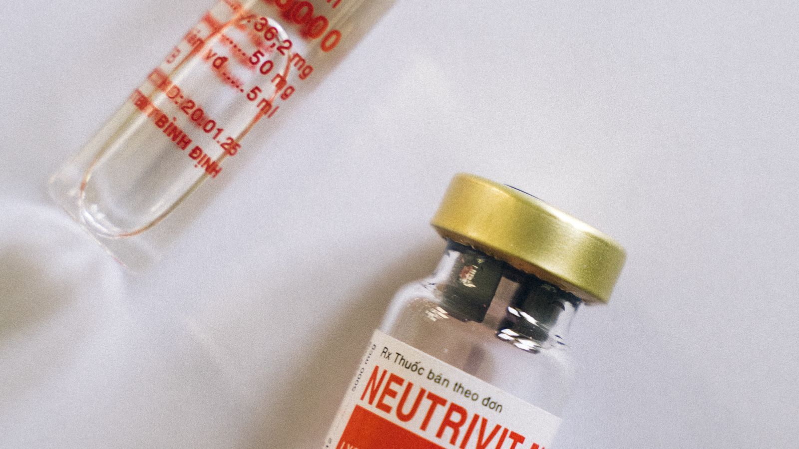 Flat lay of a healthcare ampule and a medicine bottle arranged on a plain white background.